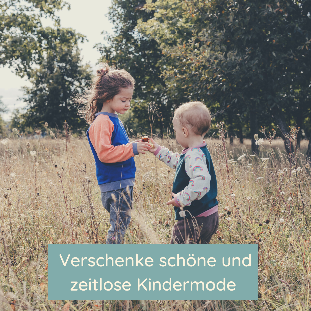 Zwei Kinder stehen auf einer Wiese und reichen sich die Hand. Beide tragen einen Oktopulli.