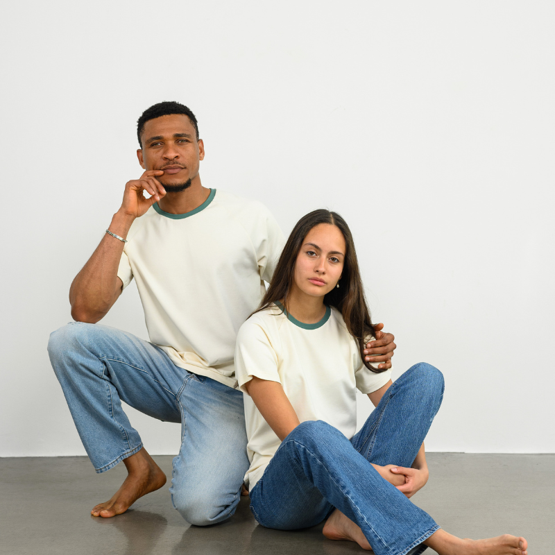 Ein Mann und eine Frau tragen ein Raglan Shirt in Weiß von Oktopulli und sitzen auf dem Boden
