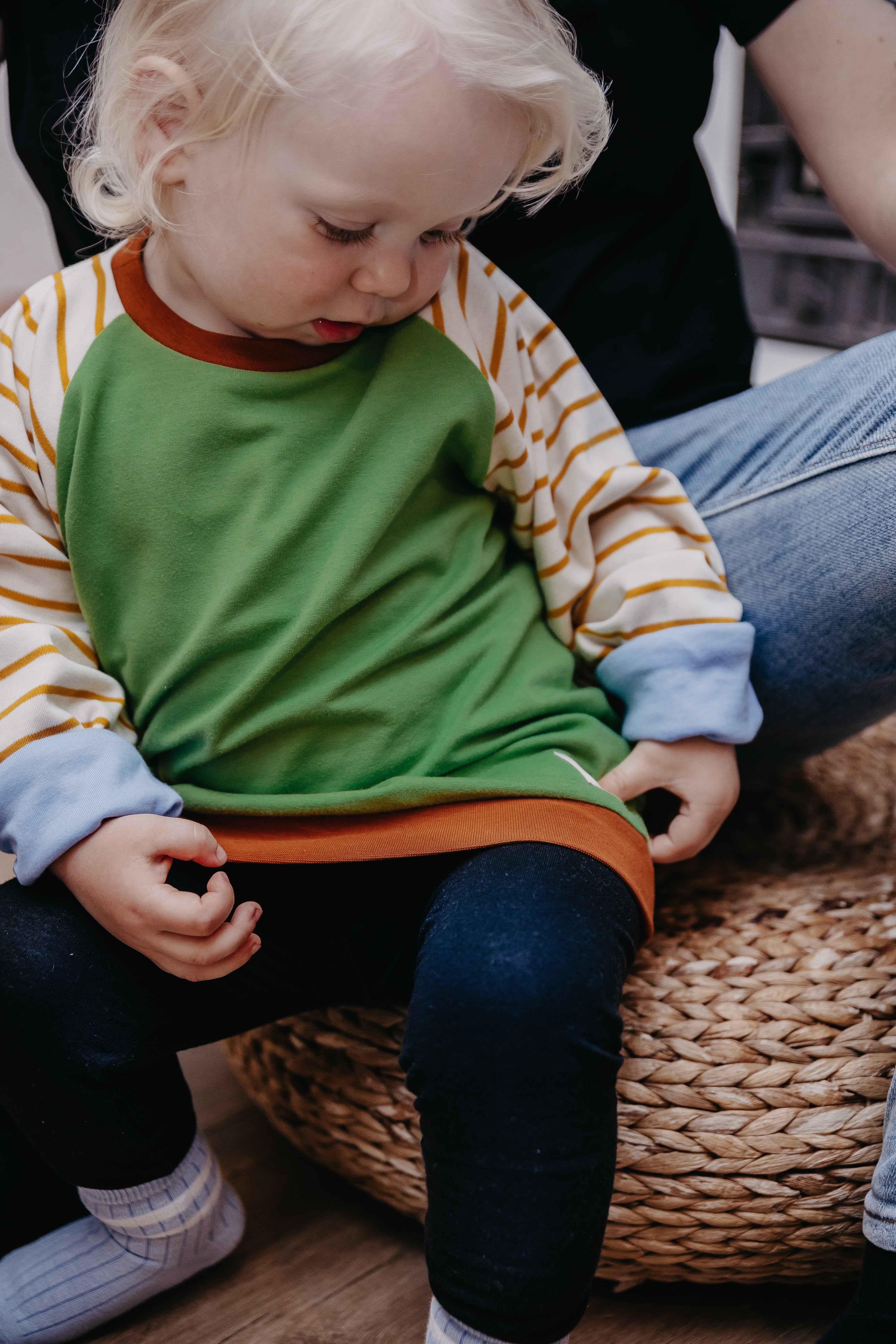 Ein Kind sitzt und trägt dabei den Alltagsbegleiter im Unisex-Schnitt aus Bio-Baumwolle von Oktopulli