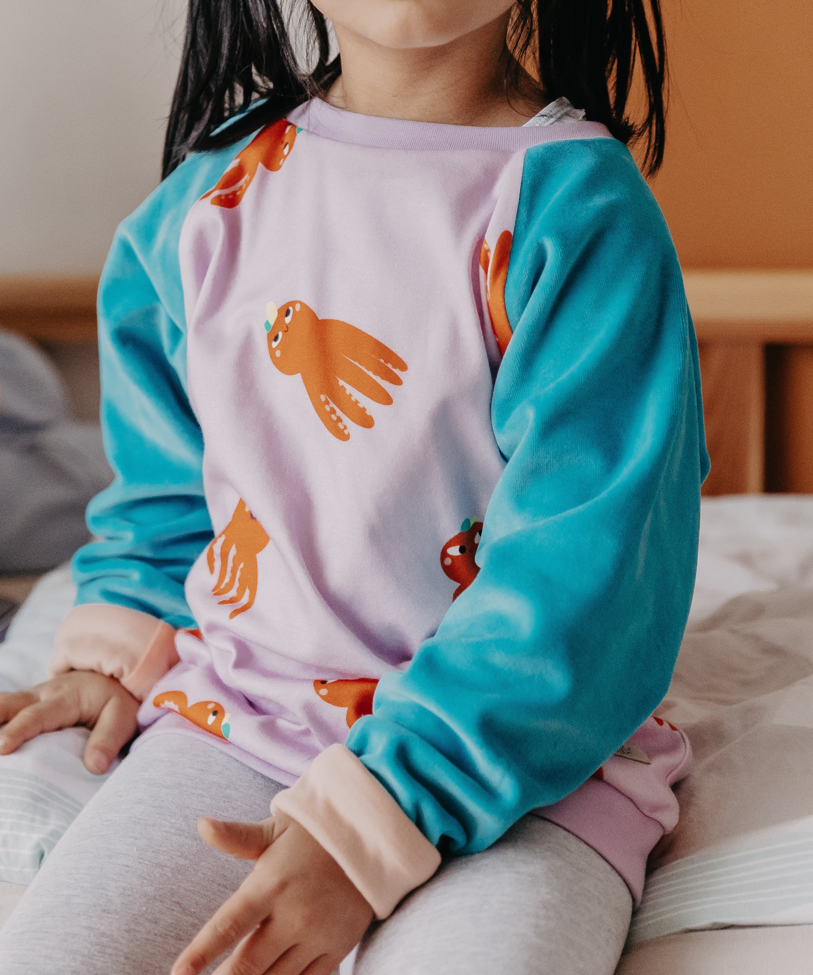 Ein Kind trägt den Alltagsbegleiter für Kinder im Oktopus-Motivstoff und blauen Ärmeln aus Bio-Baumwolle von Oktopulli