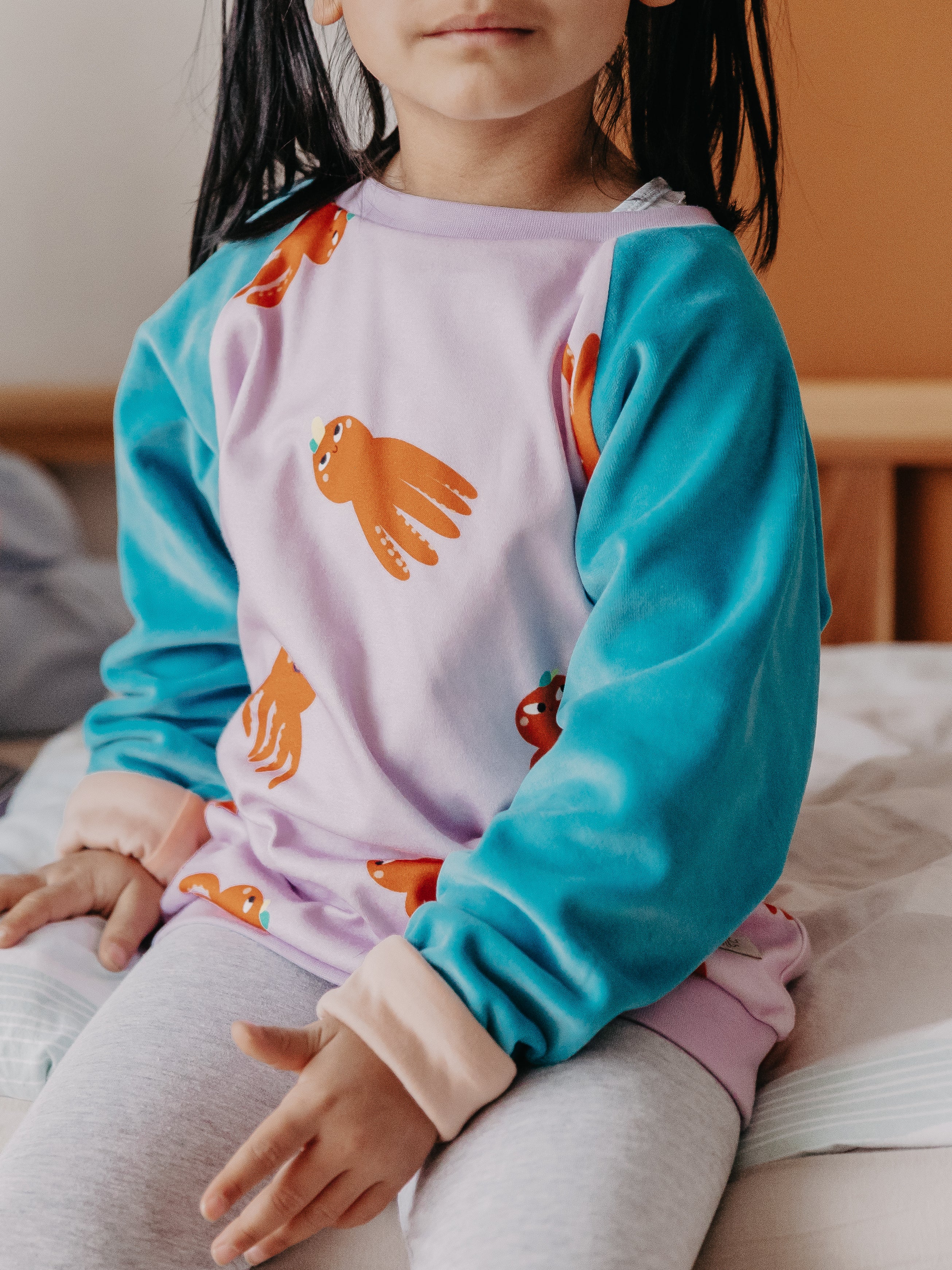 Ein Kind trägt den Alltagsbegleiter für Kinder im Oktopus-Motivstoff und blauen Ärmeln aus Bio-Baumwolle von Oktopulli